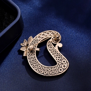 Vintage gouden D-vormige broche met bladmotieven en veiligheidsspeld op zijde