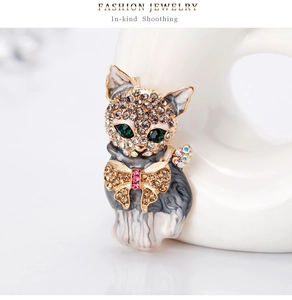 Detail of a cat brooch with green crystal eyes and enamel coating on a ceramic stand