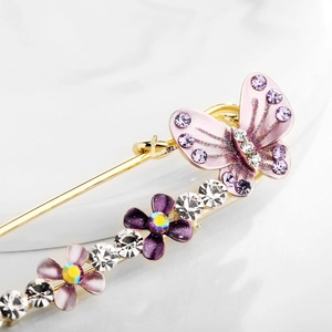 Detailed macro view of a floral safety pin brooch with crystals and purple butterfly