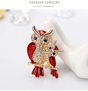 Detail of red enamel owl brooch with sparkling rhinestones on golden branches