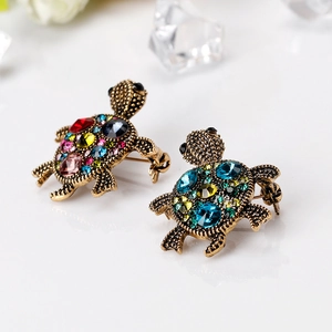 Vintage gold turtle brooches set with colorful faceted rhinestones on a white surface