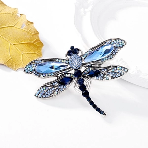 Elegant dragonfly brooch featuring blue crystals and silver-tone alloy on a white background