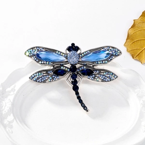 Detail of dragonfly brooch with blue rhinestones on a white porcelain plate