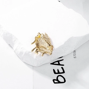 Back view of gold beetle brooch with safety rotating lock pin on white stone base