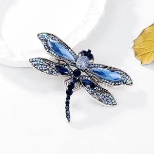 Vintage silver dragonfly brooch with blue rhinestones and crystals on white background