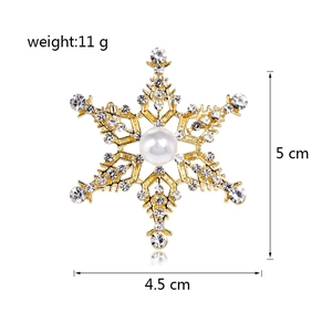 Elegante broche de copo de nieve con base dorada, cristales y perla central