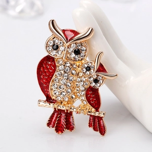 Elegant gold-tone owl brooch with red enamel and sparkling rhinestones on a white hand model
