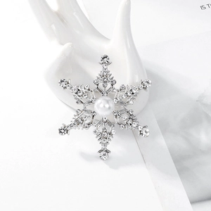 Broche de copo de nieve brillante con pedrería y perla sobre un soporte de exhibición