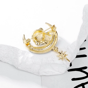 Cute golden moon and star astronaut brooch with matte finish on a white stone background