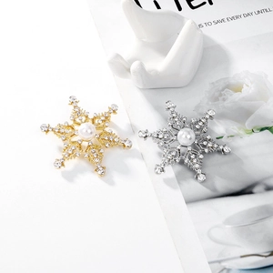Vista macro detallada de broches de copo de nieve con strass y perlas blancas en oro y plata
