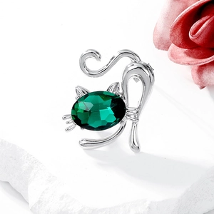 Macro shot of silver cat brooch featuring a large green crystal on a white stone