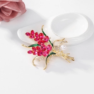 Eleganter Blumen-Brosche mit rosa Edelsteinen und Perlen auf weißem Keramiksockel
