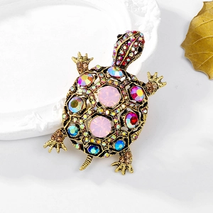 Detailed close-up of a vintage turtle brooch with colorful crystals on a white plate