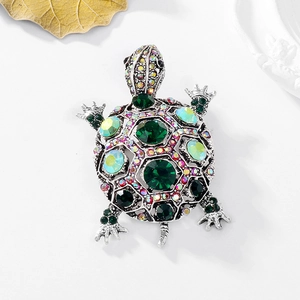 Macro shot of silver turtle brooch with green rhinestones and colorful crystal details