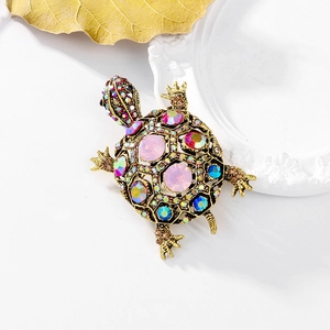 Close-up of vintage gold turtle brooch with colorful rhinestones and pink crystals