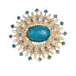Vintage gold sunburst brooch featuring a green center stone and multicolored crystals