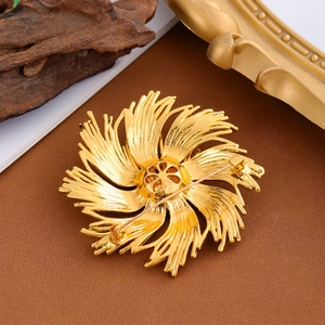 Vintage gold fireworks brooch with secure safety clasp and detailed brushed metal texture