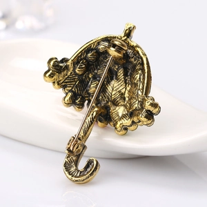 Achteraanzicht van vintage gouden paraplubroche met gedetailleerd snijwerk en speld