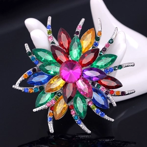 Elegante broche de flor de cristal multicolor con pedrería sobre un soporte de mano de cerámica