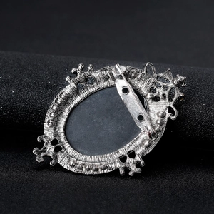 Vintage silver metal brooch back view featuring ornate hollow frame and secure safety pin