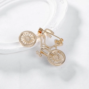 Spilla vintage a forma di bicicletta dorata con strass su sfondo bianco