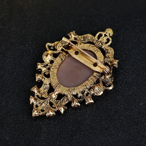 Back view of vintage gold-tone portrait brooch with intricate relief patterns and pin clasp