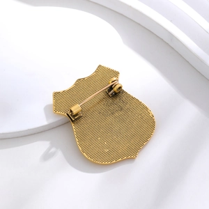Golden shield metal badge back view with safety pin and textured grid pattern