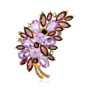 Elegant floral brooch with purple and red crystal gemstones on a gold-plated base