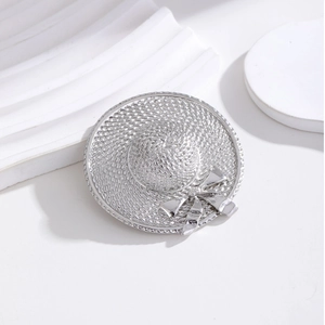 Elegante silberne Strohhut-Brosche mit Webstruktur und Metallschleife auf weißem Sockel