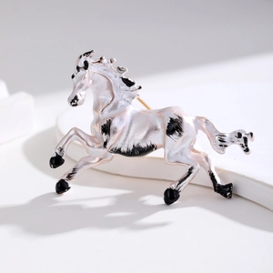 Elegant white enamel galloping horse brooch with black spots on a white stone background
