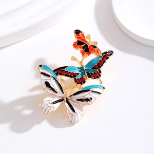 Three-butterfly brooch with colorful enamel wings and rhinestones on a white surface