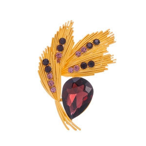 Macro shot of golden wheat brooch with teardrop purple gemstone and violet crystal detail