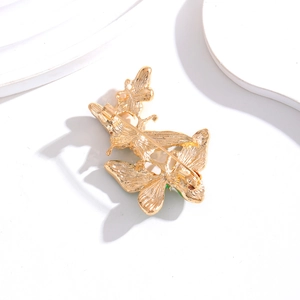 Back view of gold-tone butterfly brooch showing detailed pin clasp on a white background