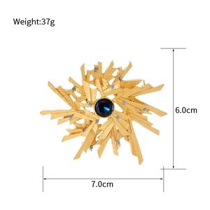 Vintage gold sunburst brooch with a large blue gemstone and sparkling rhinestones