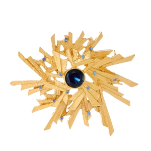 Golden snowflake brooch with dark blue stone and light blue crystals on white background