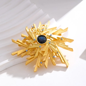 Vintage sunburst brooch with blue rhinestone centerpiece in brushed gold finish