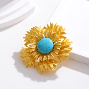 Vintage golden layered petal flower brooch with a turquoise gemstone center on white base