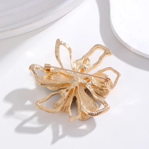Golden flower brooch back view showing metal hollow texture and safety pin clasp