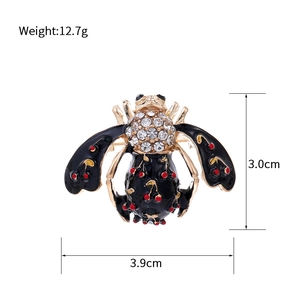 Macro de la broche abeille avec émail noir, pois rouges cerise et strass brillants