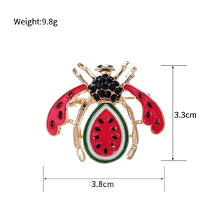 Vue macro d'une broche abeille dorée avec ailes rouges et abdomen en motif pastèque