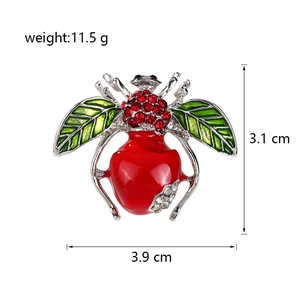 Détail macro de la broche abeille montrant les ailes en émail et les cristaux rouges avec taille