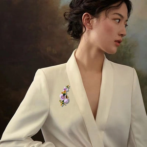 Elegant iris flower brooch in purple and yellow enamel on a white suit jacket