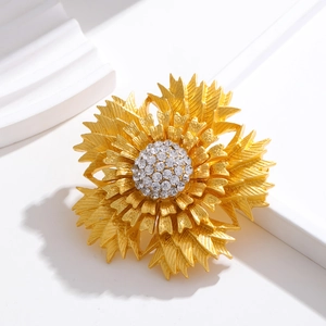 Vintage gold layered flower brooch with crystal inlay on a minimalist white pedestal