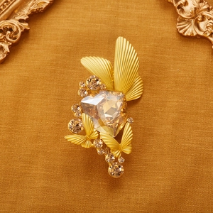 Vintage gold butterfly brooch with large champagne crystal on textured fabric background