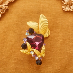 Detailed macro view of a vintage crystal butterfly brooch with a large purple gemstone