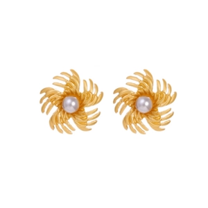 Détail de boucles d'oreilles vintage dorées avec pétales en spirale et perles blanches