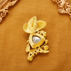 Exquisite gold butterfly brooch with grey crystal gemstone on textured vintage background