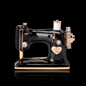 Vintage sewing machine brooch with black enamel and sparkling rhinestones on black background