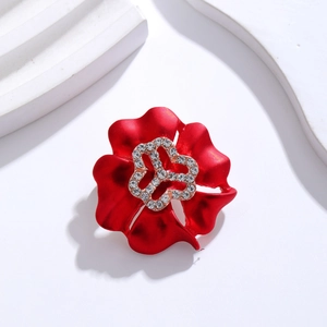Détail d'une broche fleur rouge avec finition mate et strass brillants sur pétales