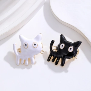 Spille a forma di gatto in smalto bianco e nero con bordo dorato su sfondo minimale